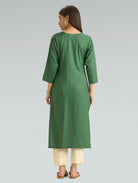 Woman wearing a green kurta with beige pants on a gray background