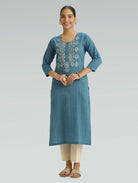 Woman wearing a blue kurta with a white pattern on a gray background