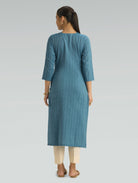 Woman wearing a blue kurta with beige pants on a light gray background