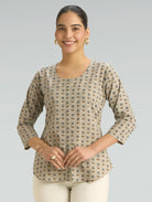 Woman wearing a patterned beige top on a gray background