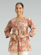 Woman wearing a floral pink top on a gray background