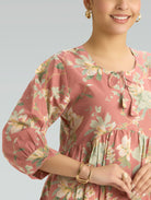 Woman wearing a pink floral dress with a plain background