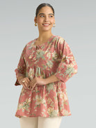 Woman wearing a floral pink top against a plain background