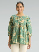Woman wearing a green floral blouse against a gray background