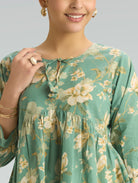 Woman wearing a green floral dress against a neutral background