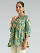 Woman wearing a green floral blouse against a gray background