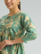Woman wearing a green floral dress against a gray background