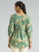 Woman wearing a green floral blouse against a gray background