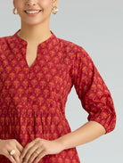 Woman wearing a red patterned kurta against a gray background