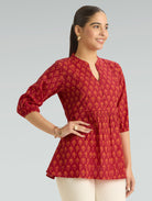 Woman wearing a red patterned top against a gray background