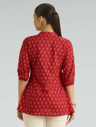 Woman wearing a red patterned top on a gray background