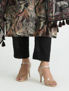 Person wearing a patterned coat with tassels, black pants, and high-heeled shoes on a white background
