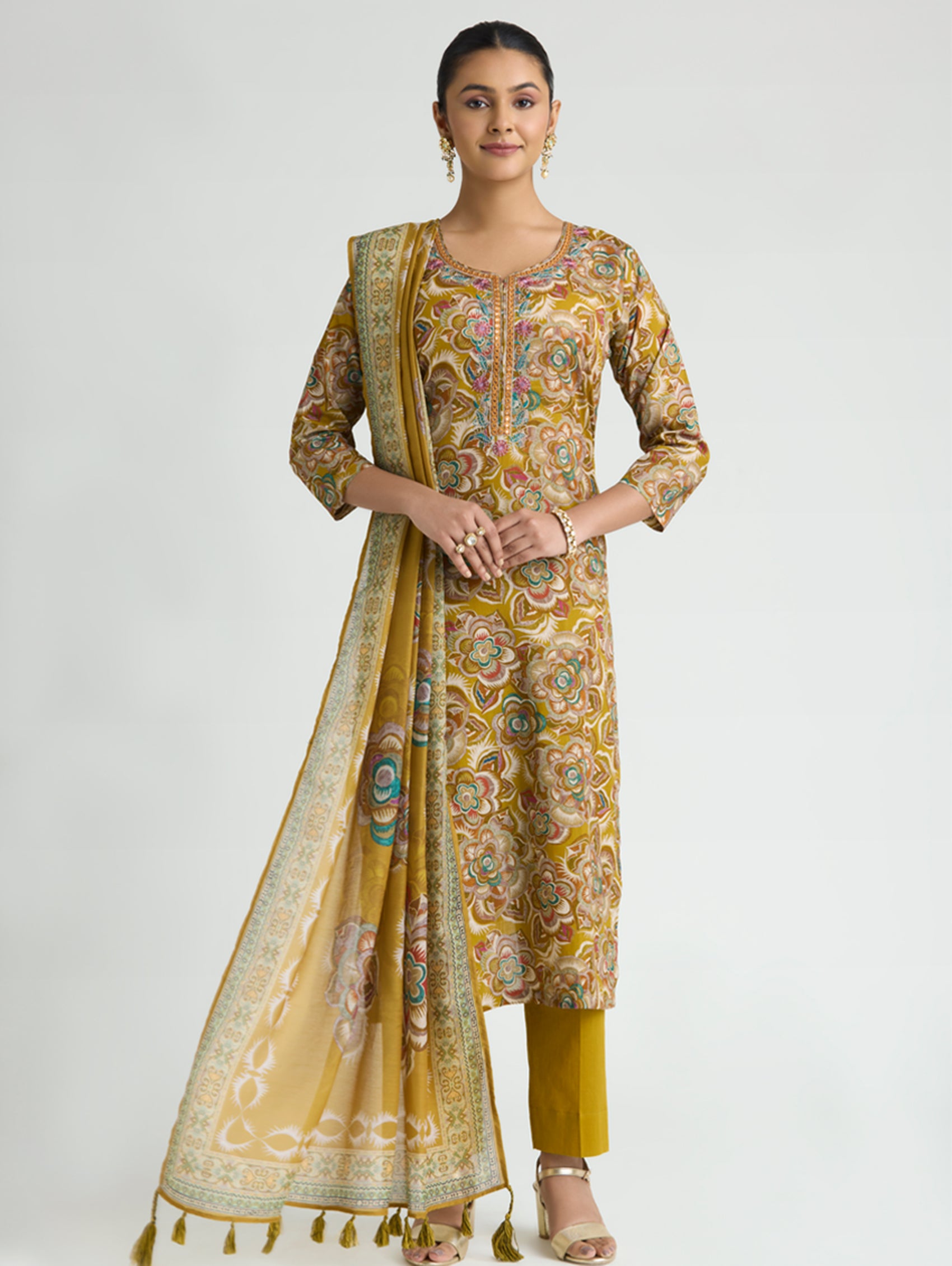 Woman wearing a traditional yellow and patterned outfit on a white background