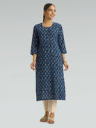 Woman wearing a blue floral kurta with beige pants on a gray background