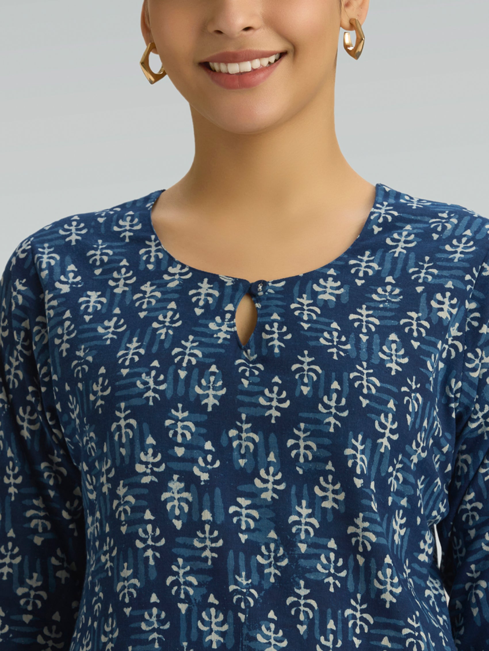 Woman wearing a blue patterned top with a plain background