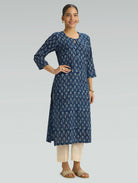 Woman wearing a blue floral kurta with beige pants on a light gray background