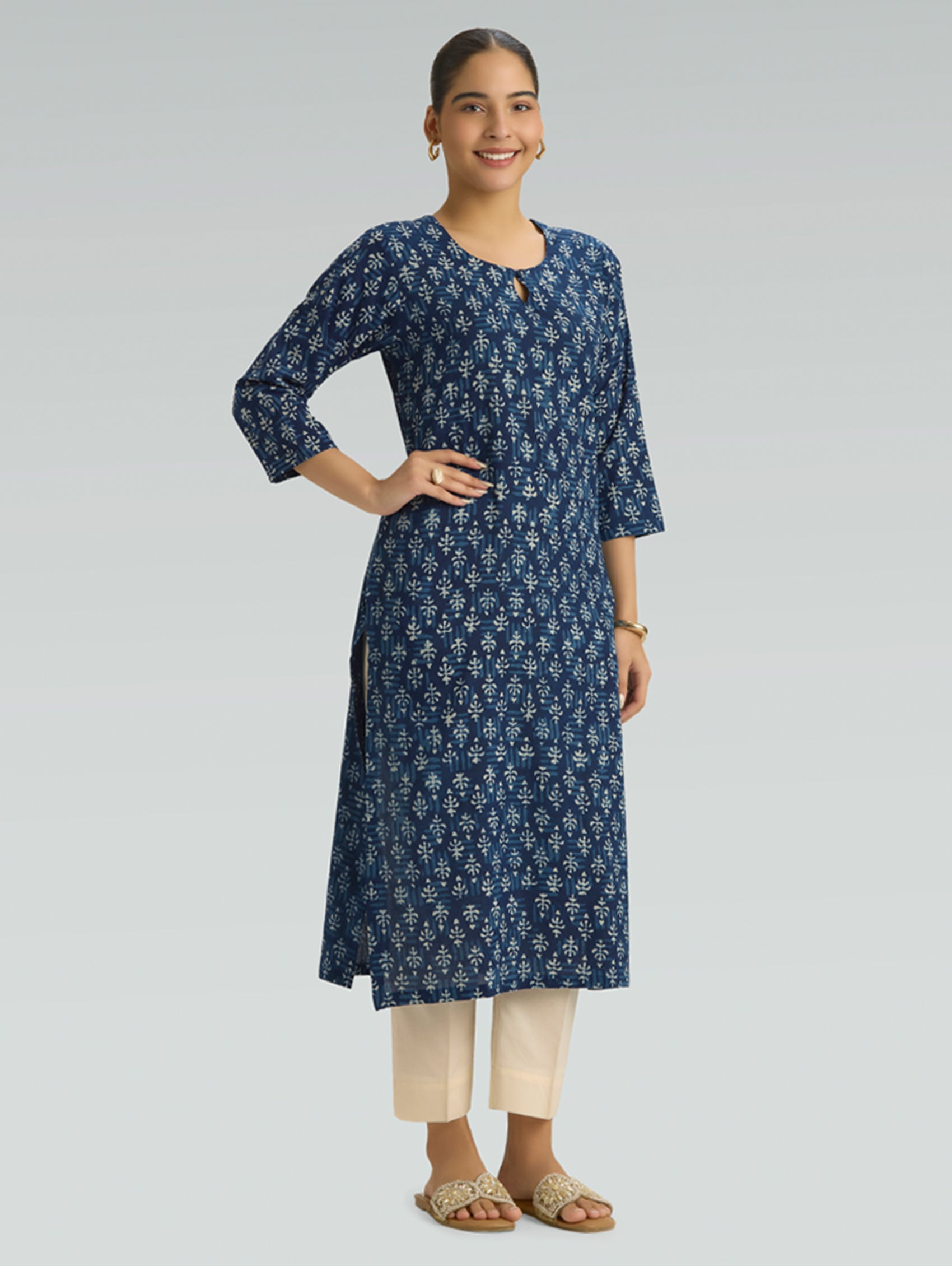 Woman wearing a blue floral kurta with beige pants on a light gray background