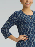 Woman wearing a blue patterned dress against a gray background