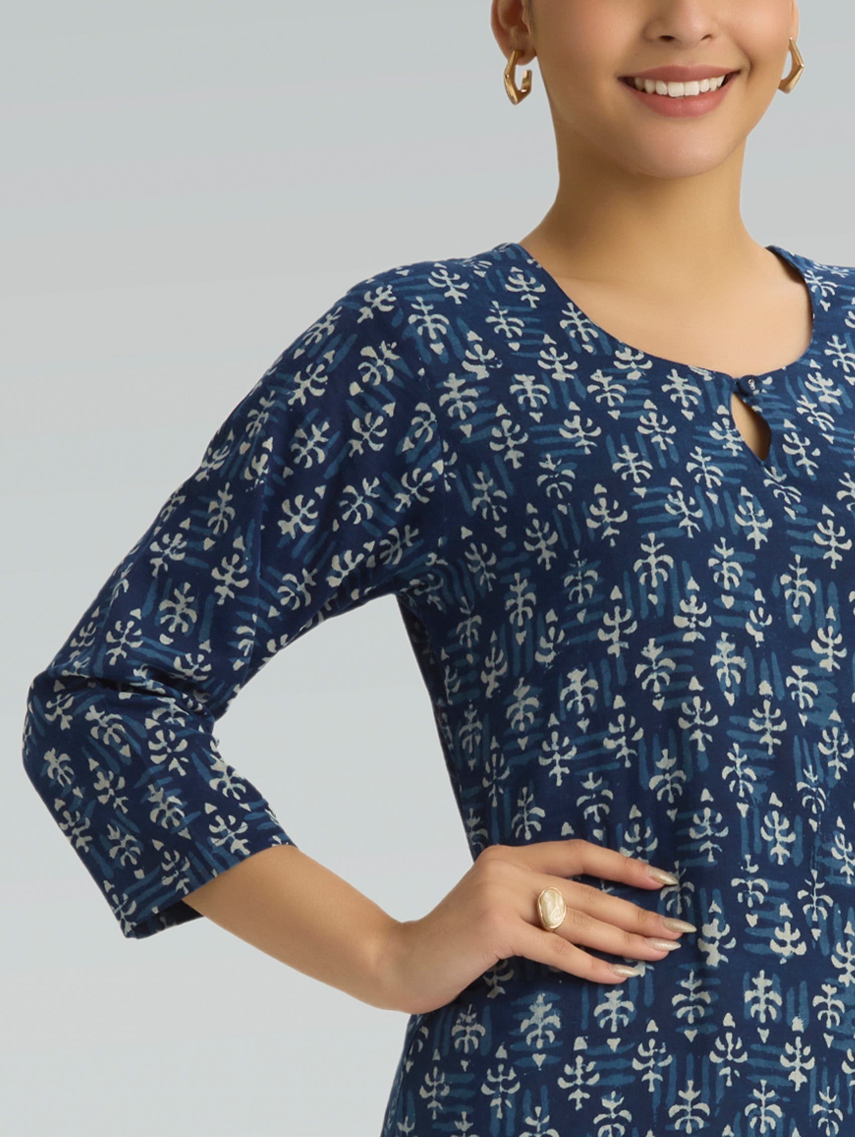 Woman wearing a blue patterned dress against a gray background