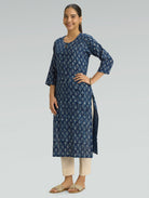 Woman wearing a blue floral kurta with beige pants on a light gray background
