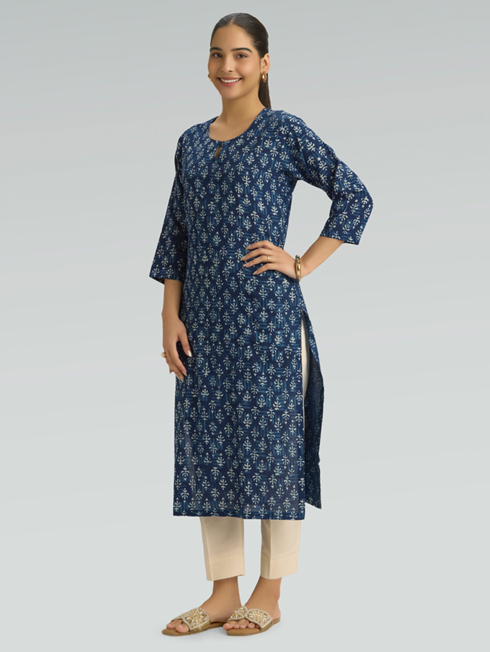 Woman wearing a blue floral kurta with beige pants on a light gray background