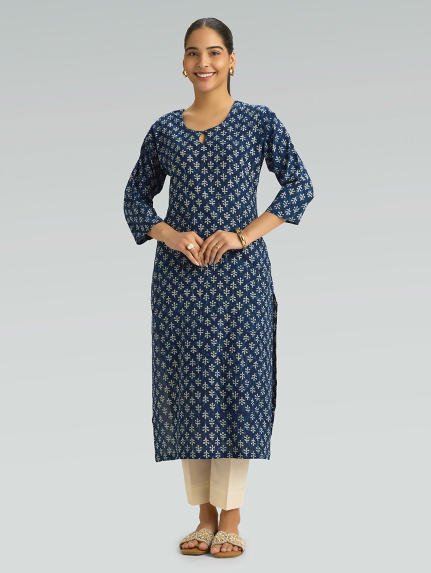 Woman wearing a blue patterned kurta with beige pants on a gray background