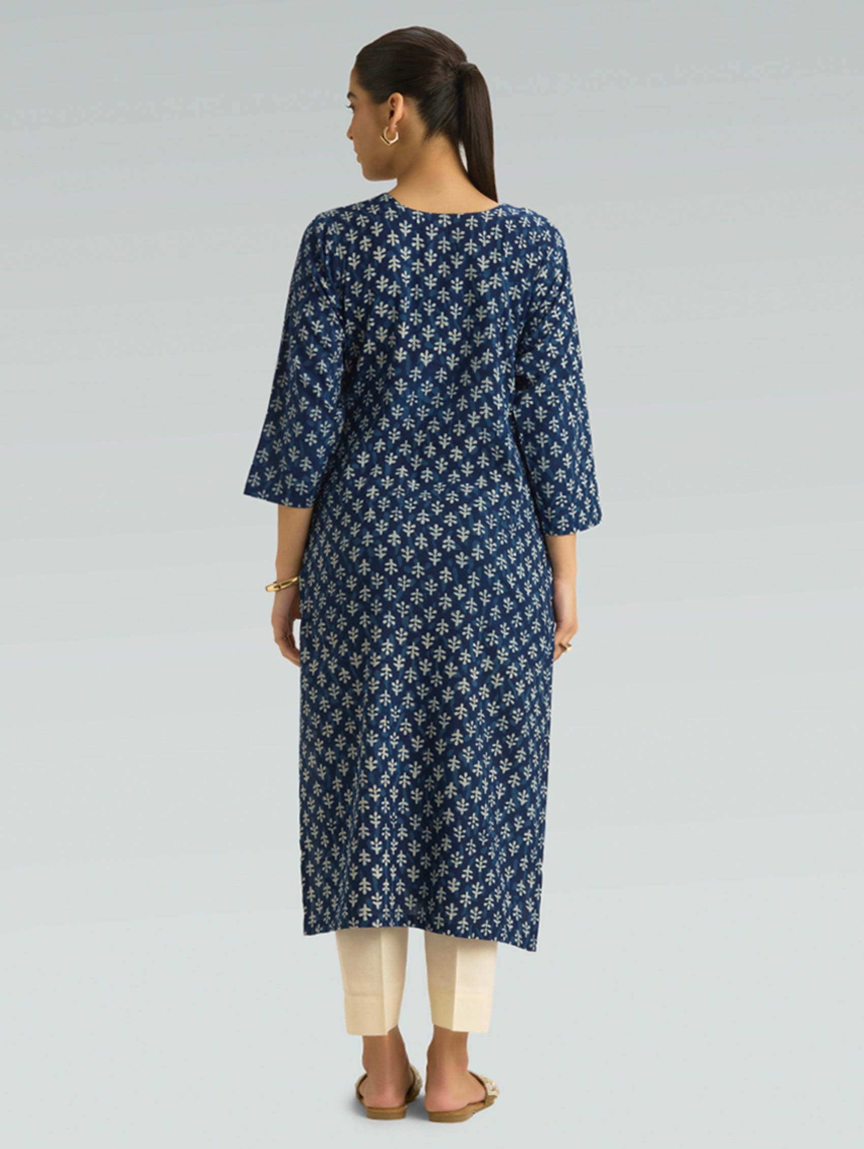 Woman wearing a blue patterned kurta with beige pants on a light gray background