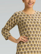 Woman wearing a patterned beige and brown dress against a gray background
