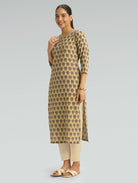 Woman wearing a patterned kurta with beige pants on a gray background
