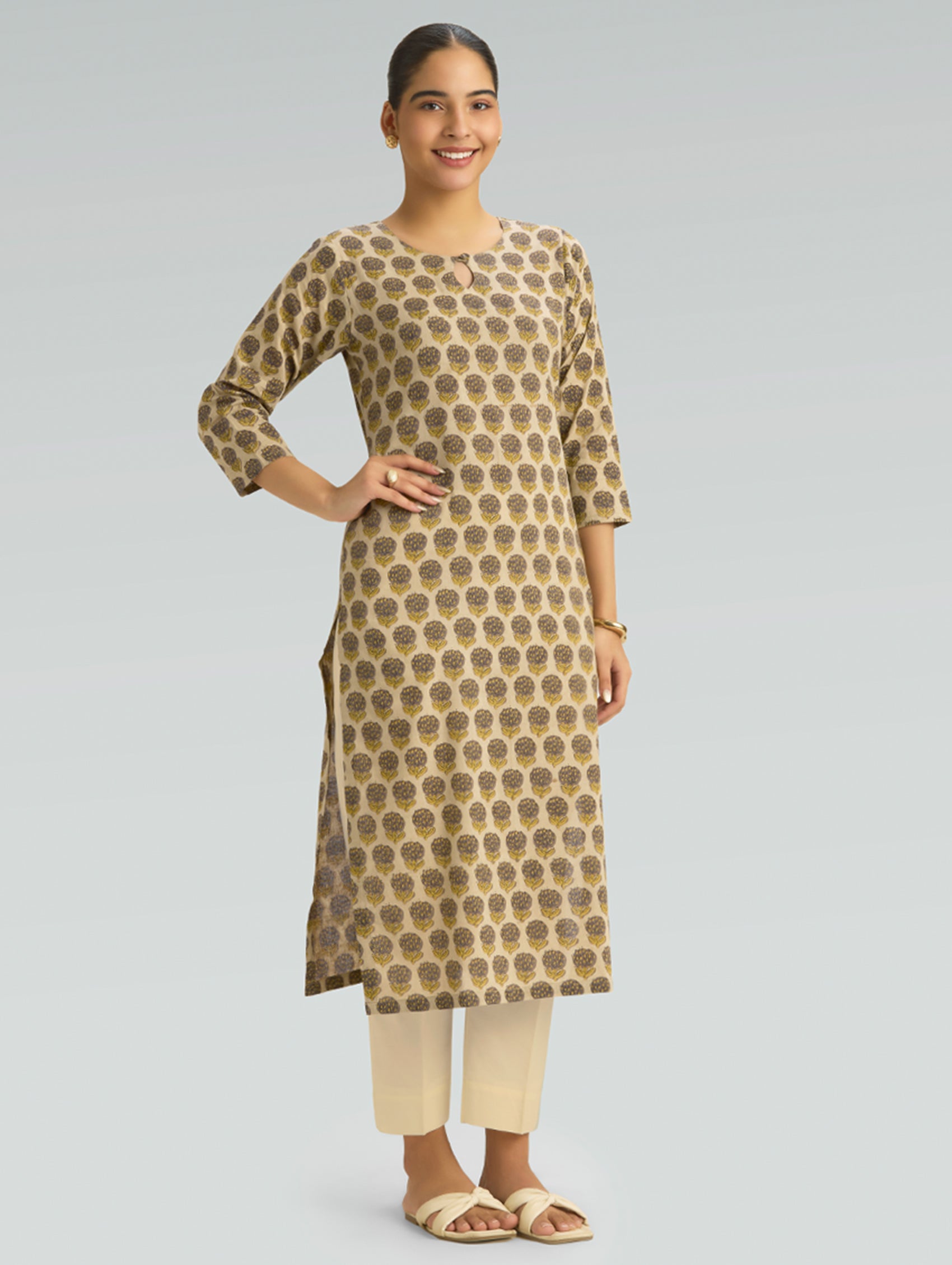 Woman wearing a patterned kurta with beige pants on a gray background