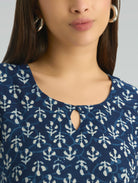Close-up of a person wearing a blue and white patterned top with a plain background