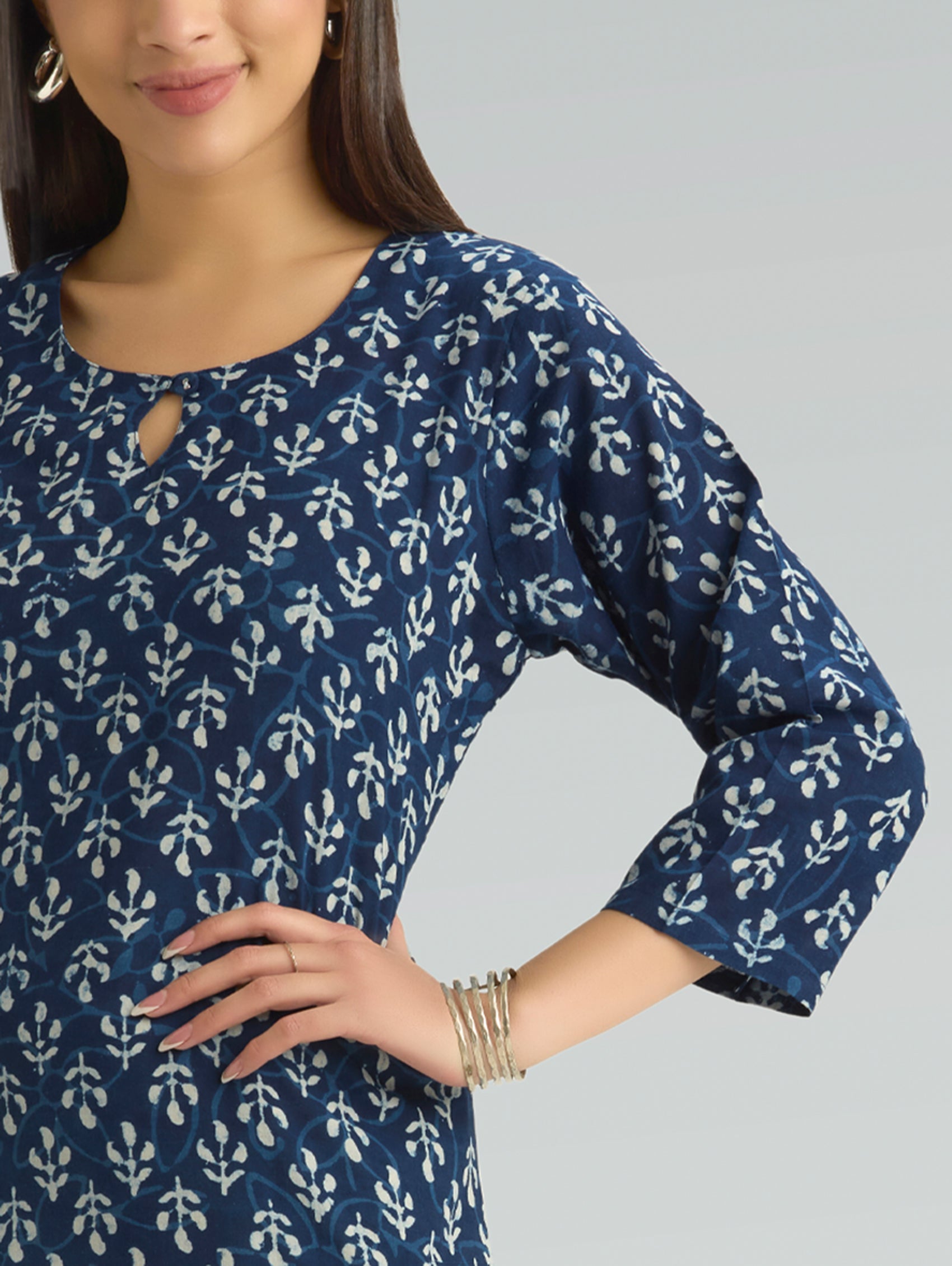 Woman wearing a blue and white patterned dress against a gray background