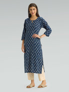 Woman wearing a blue patterned kurta with beige pants on a gray background