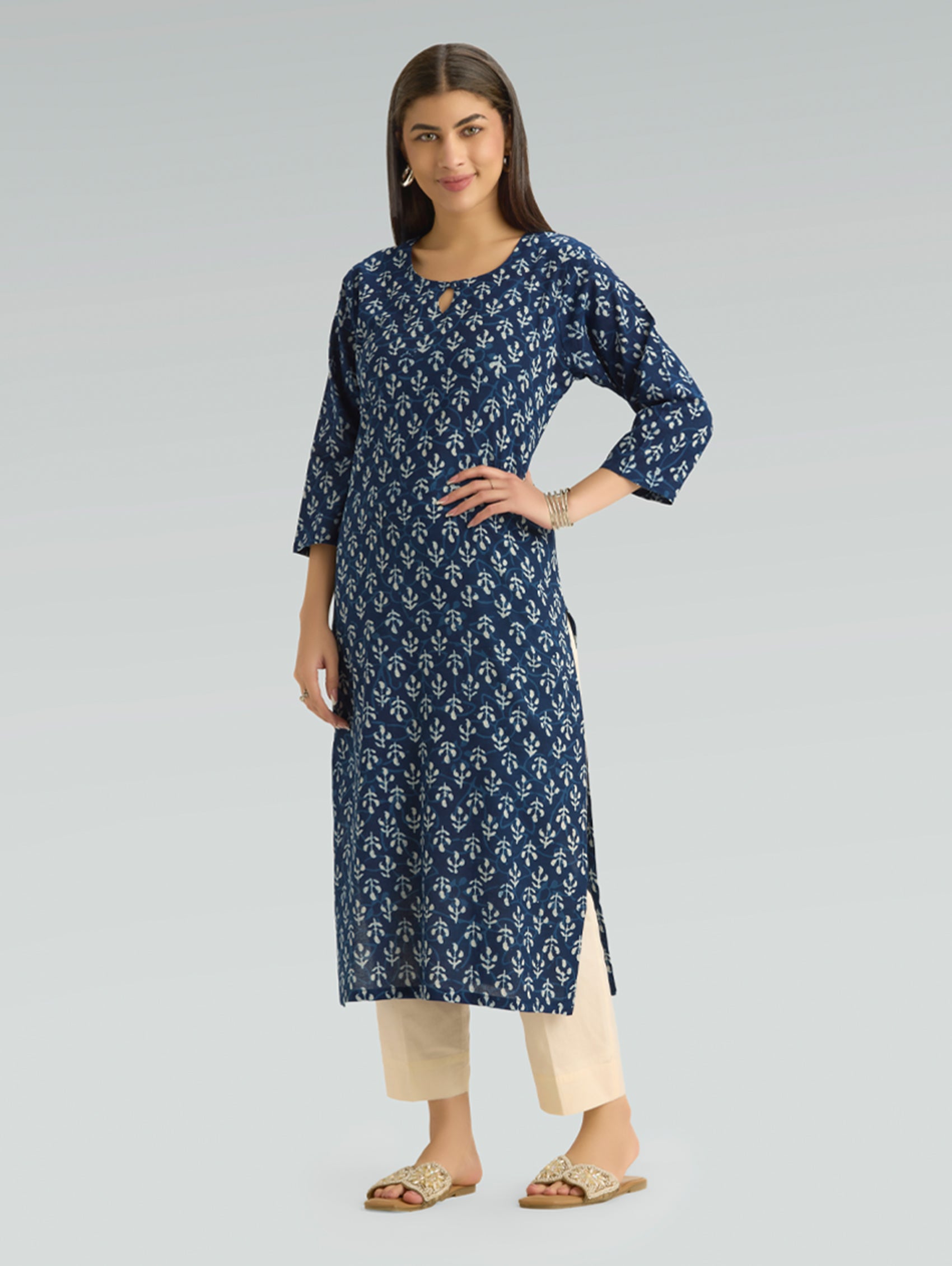 Woman wearing a blue patterned kurta with beige pants on a gray background