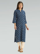 Woman wearing a blue floral patterned kurta with beige pants on a gray background