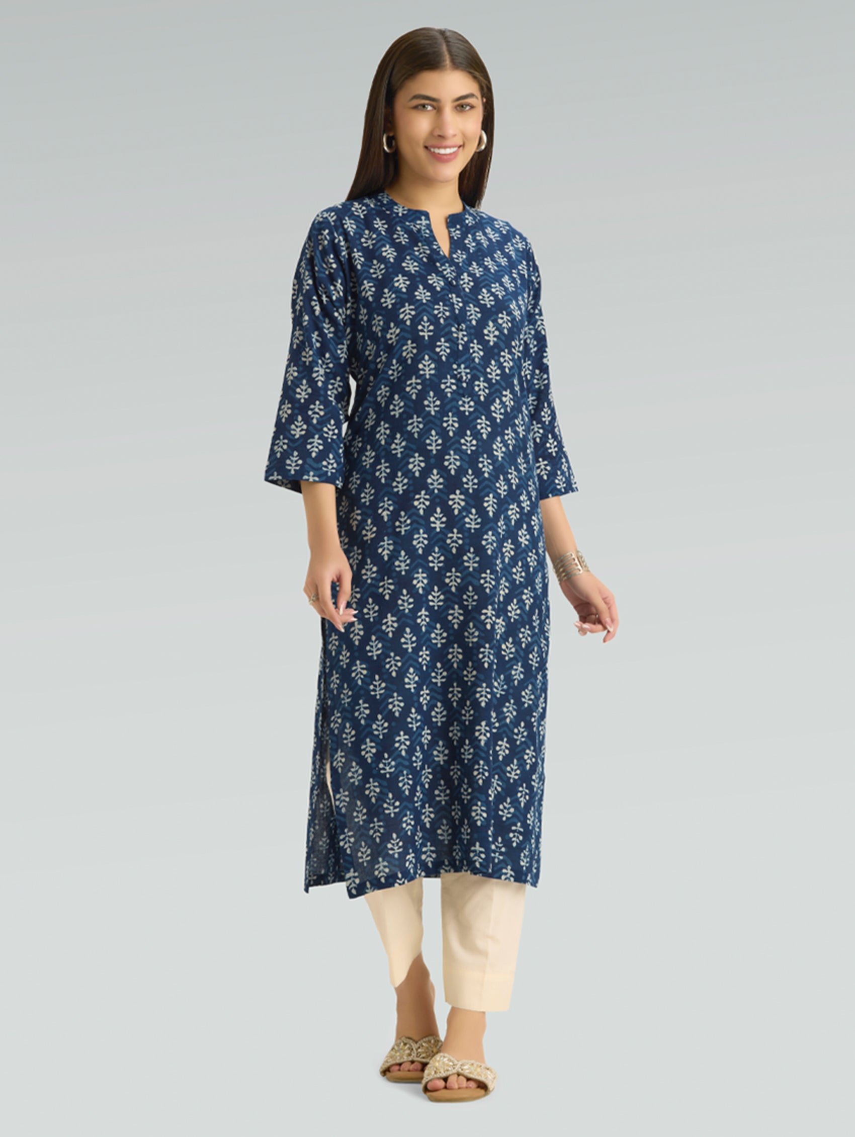 Woman wearing a blue floral patterned kurta with beige pants on a gray background