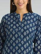 Woman wearing a blue patterned shirt with a neutral background