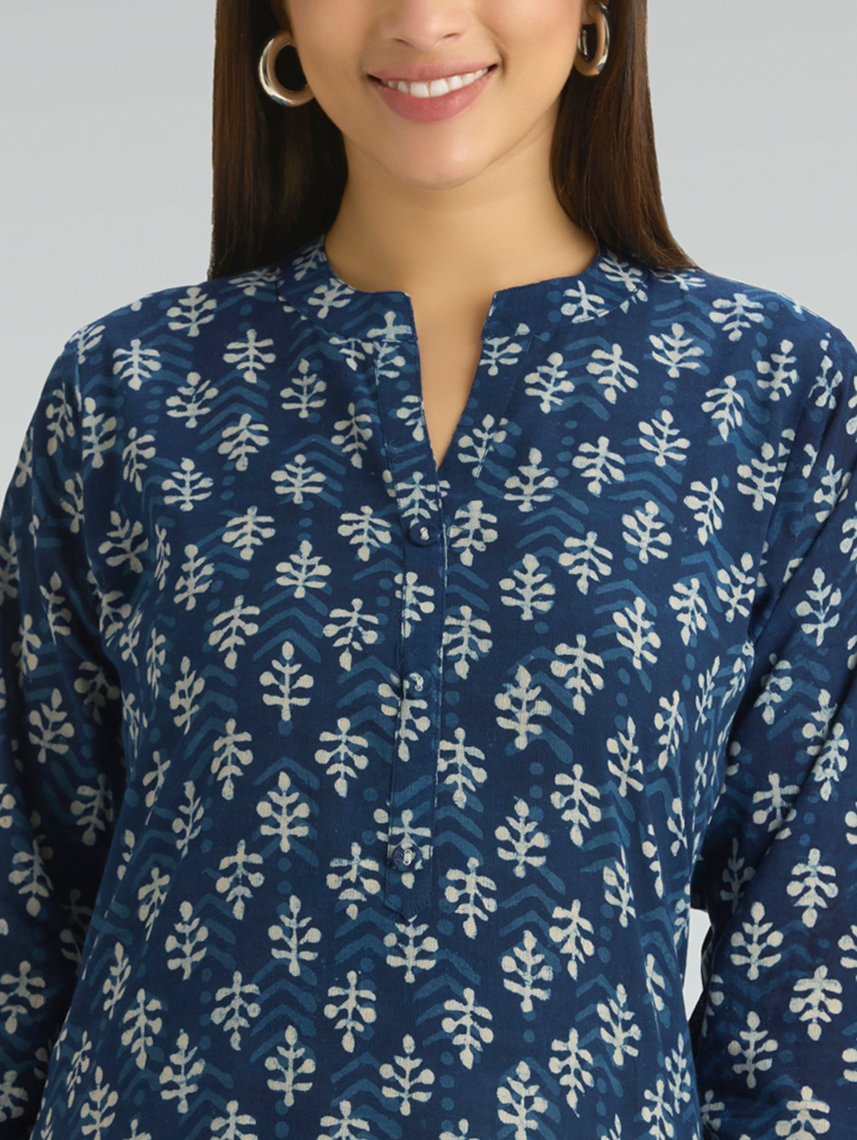 Woman wearing a blue patterned shirt with a neutral background