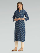 Woman wearing a blue floral kurta with beige pants on a gray background