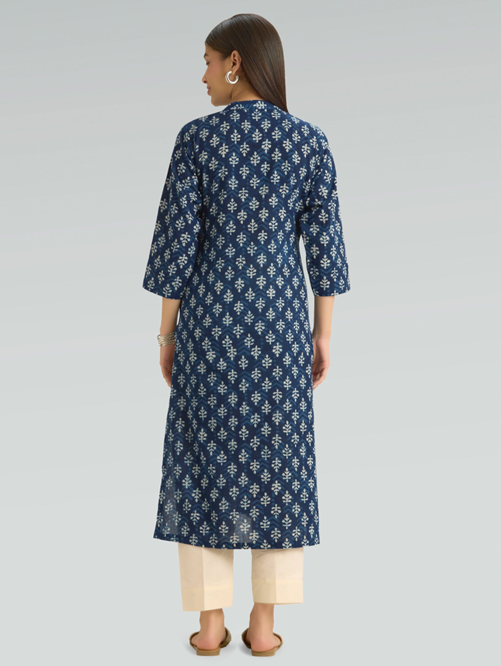 Woman wearing a blue patterned kurta with beige pants on a light gray background