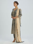 Woman wearing a traditional outfit with a long embroidered jacket and beige dupatta on a light gray background