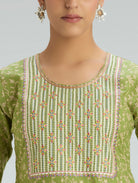 Green embroidered top worn by a person on a gray background
