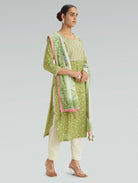 Woman wearing a green and white traditional outfit with a light gray background