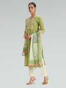 Woman wearing a green and white traditional outfit with a floral dupatta on a gray background