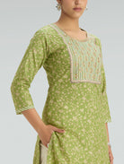 Green traditional outfit with intricate detailing on a gray background