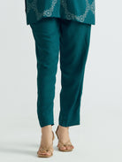 Teal tapered ankle-length pants with side seams, styled with tunic hem